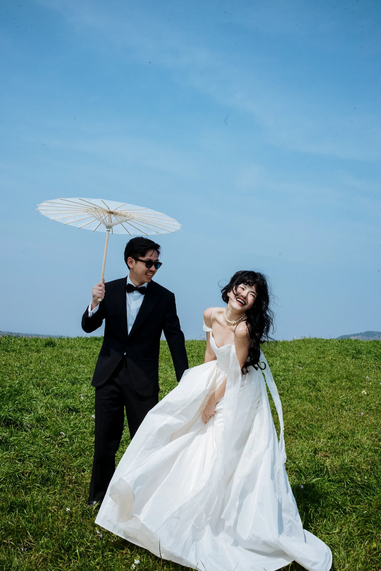 Vũ and Thi twirling with umbrella on the green