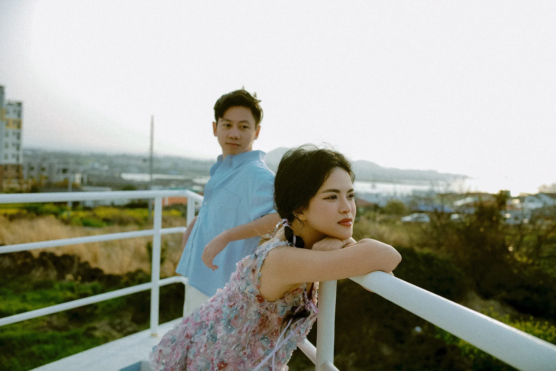 Vũ and Thi leaning on a white railing overlooking the city